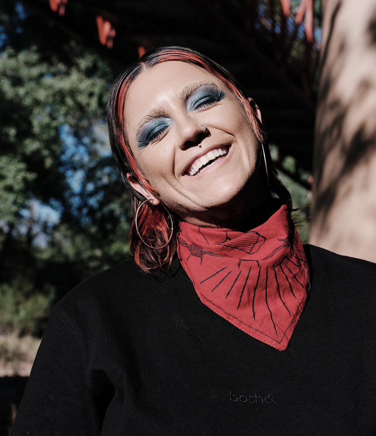 Smiling model with red bandana around their neck and black shirt