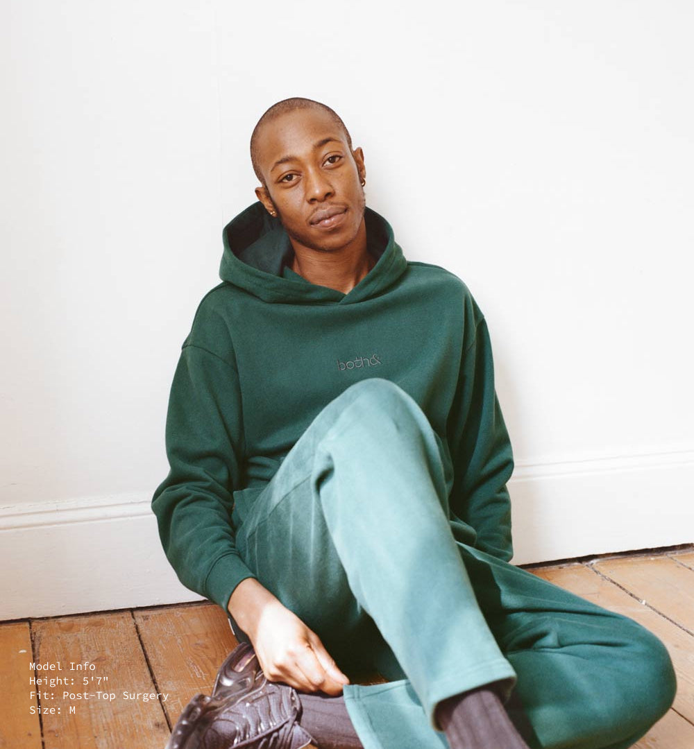 5'7" model, post-top surgery, in M forest green hoody and sweatpants